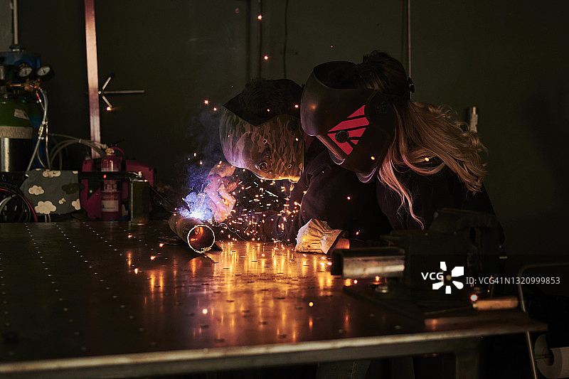 男女技工戴防护头盔进行焊接图片素材