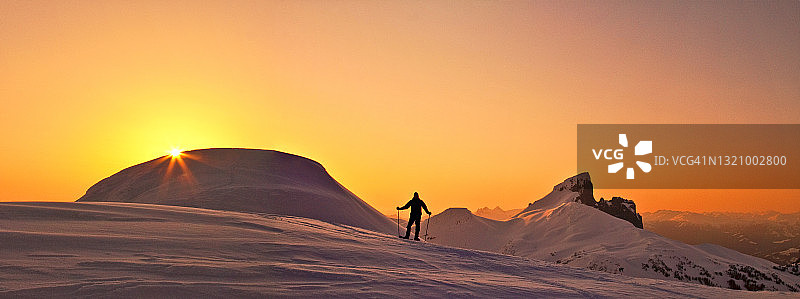 日落时分，探险者在白雪皑皑的山脊上的全景图片素材