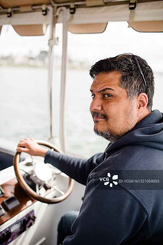 四十多岁的西班牙裔男人在圣地亚哥海湾开船图片素材