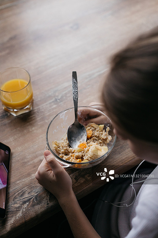 女孩吃早餐并看手机图片素材