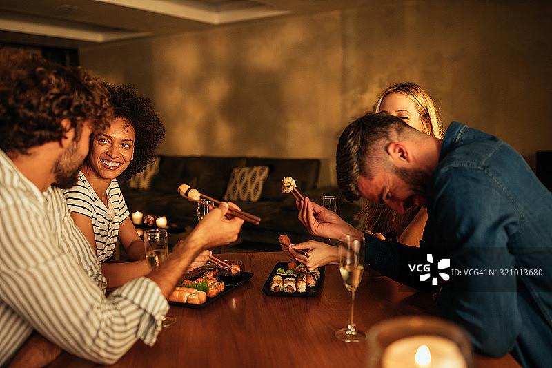 朋友们坐在餐桌旁吃寿司图片素材
