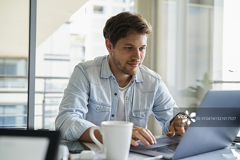 设计编辑在早餐时用笔记本电脑工作图片素材