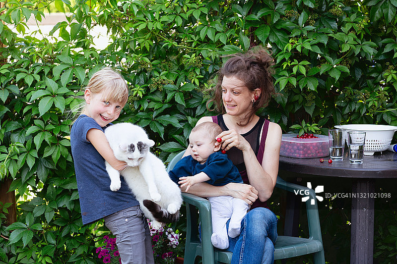 夏日乐趣：孩子们在后院和小猫玩耍图片素材
