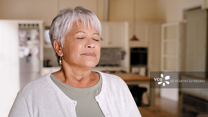 年长的女人若有所思地站在厨房里图片素材