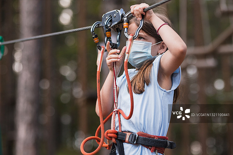 戴着防护口罩的小女孩在滑索上图片素材