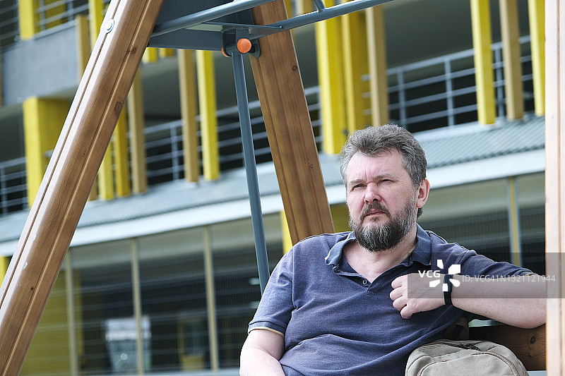 中年男人在居民区秋千上等待图片素材