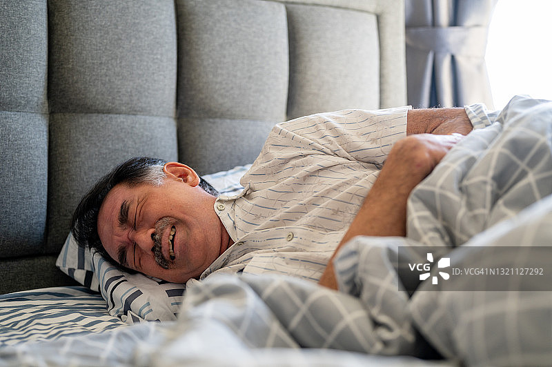 生病的老年亚洲男人捂着肚子图片素材