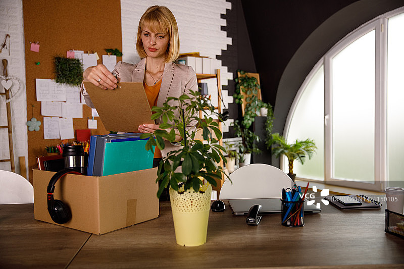 商务人士被解雇后整理办公桌上的工作文件和办公用品图片素材