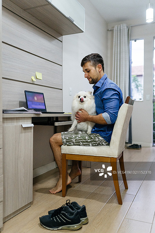 男人在家工作时抱着狗图片素材