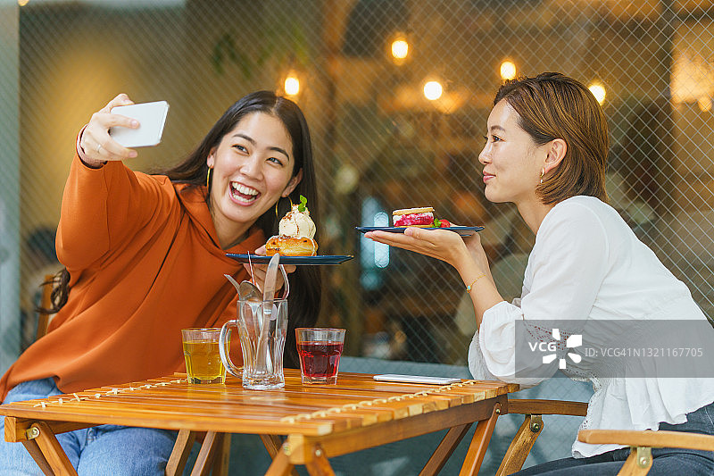 女朋友们在咖啡馆享受美食，分享社交媒体图片素材