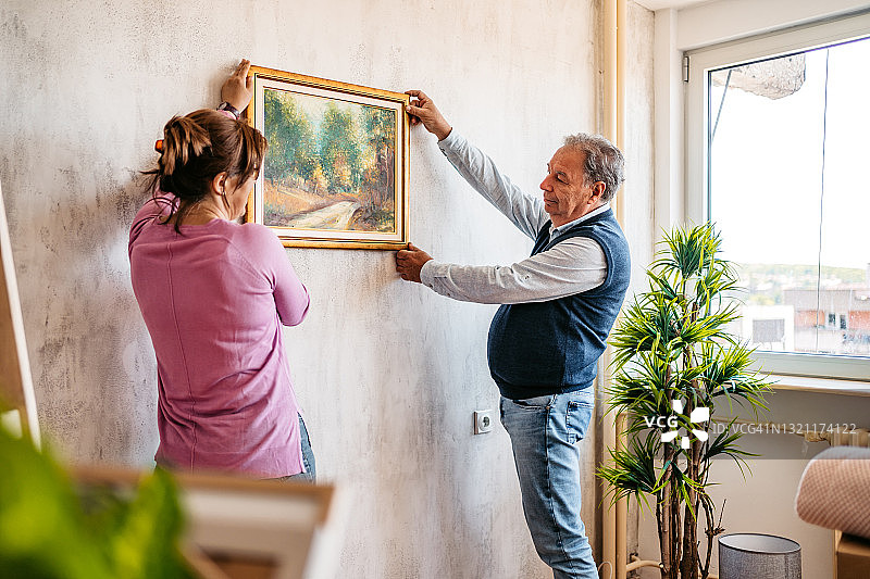 老年夫妇在墙上挂画图片素材