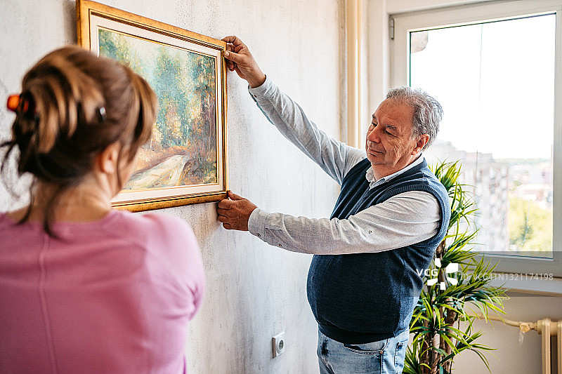 老年夫妇在墙上挂画图片素材
