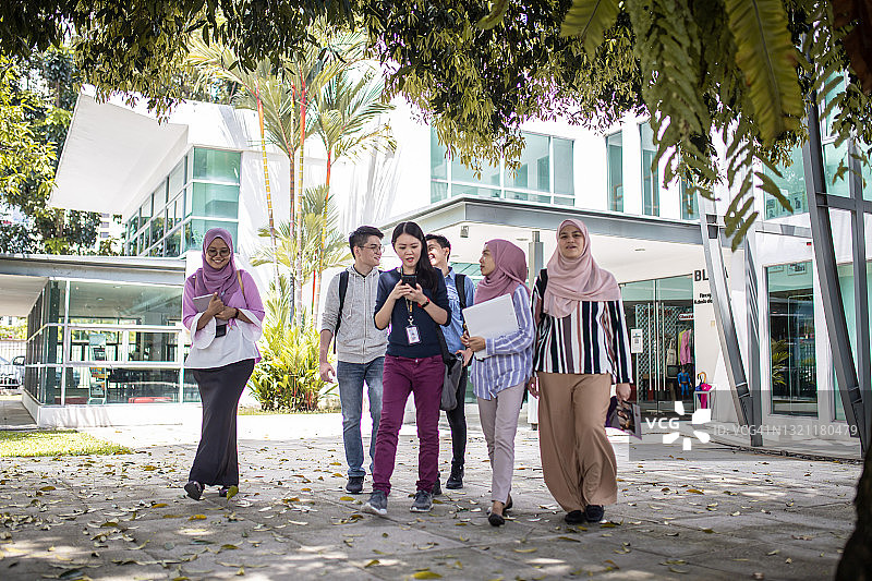 亚洲大学生从教学楼出来交谈图片素材