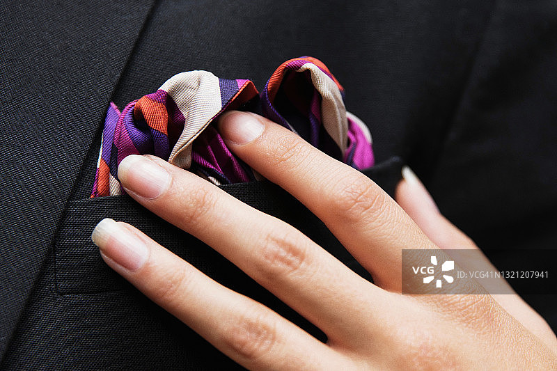 女士的手轻轻触摸男人西装胸前口袋里的优雅手帕图片素材