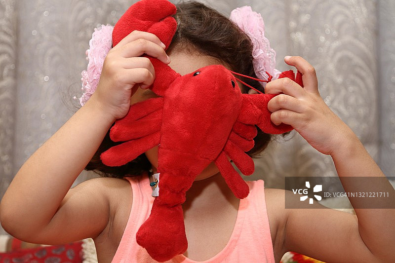 小女孩用毛绒玩具遮住脸图片素材