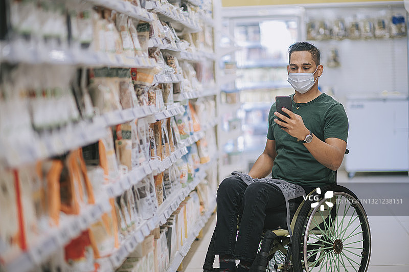 周末，坐轮椅的印度裔残疾男子与朋友在超市通过智能手机进行视频购物图片素材