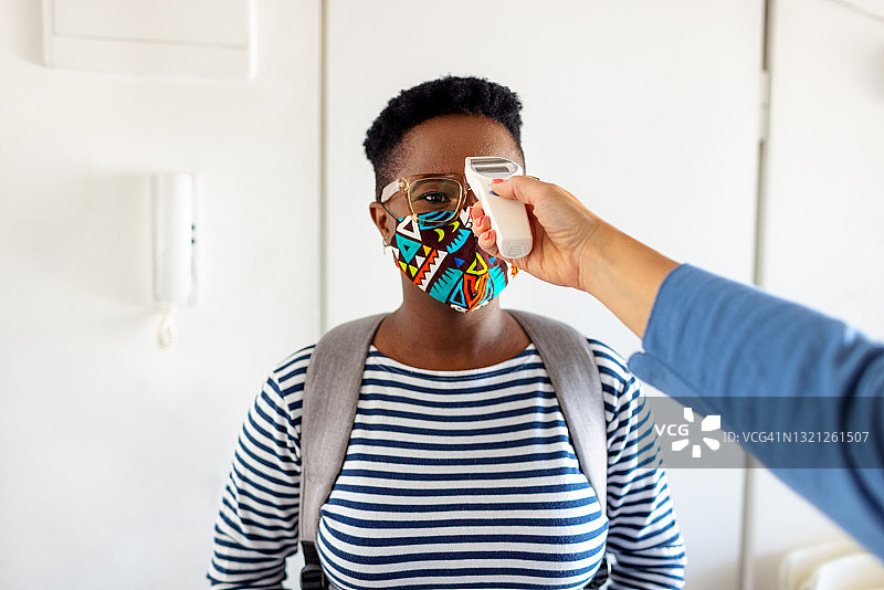 年轻女人用红外线温度计测量体温图片素材