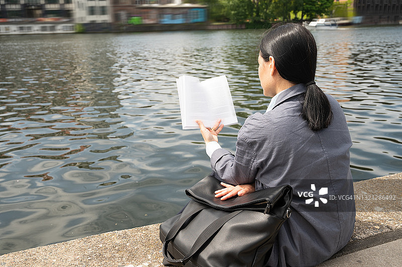 在德国柏林城市河岸边读书的女子背影图片素材