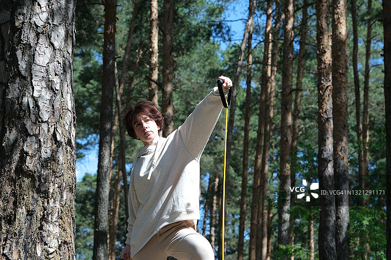 中年妇女在公园使用阻力带锻炼手臂图片素材