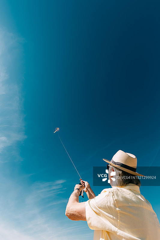 年长的男人在海滩上放飞彩色彩虹风筝图片素材