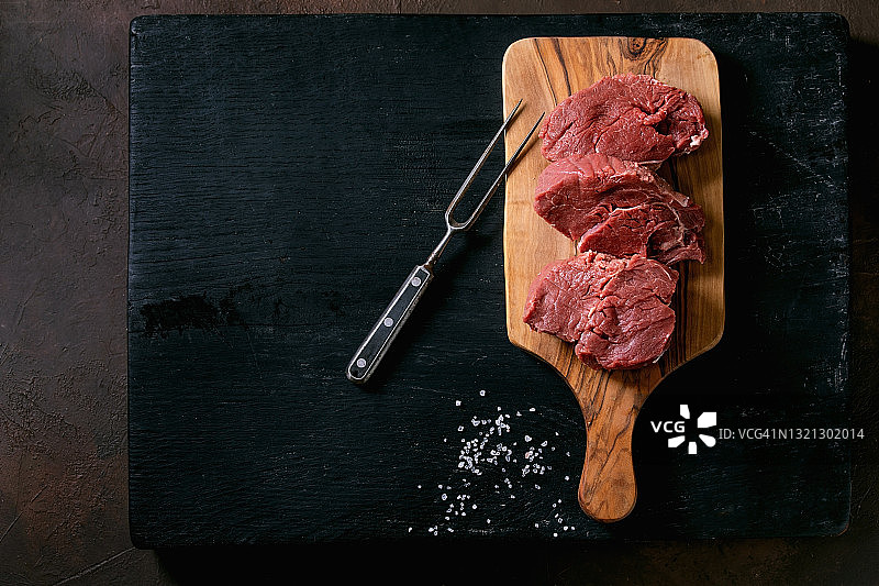 新鲜完整生牛里脊肉，置于木板上图片素材