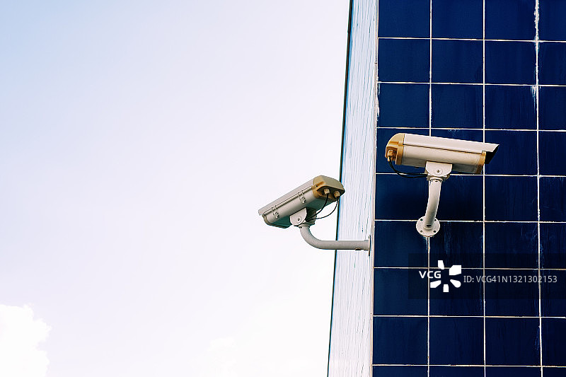 高楼蓝色瓷砖墙上的两个监控摄像头图片素材