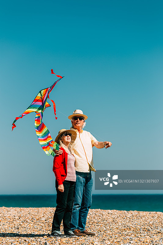 老年夫妇在海滩放飞彩色彩虹风筝图片素材