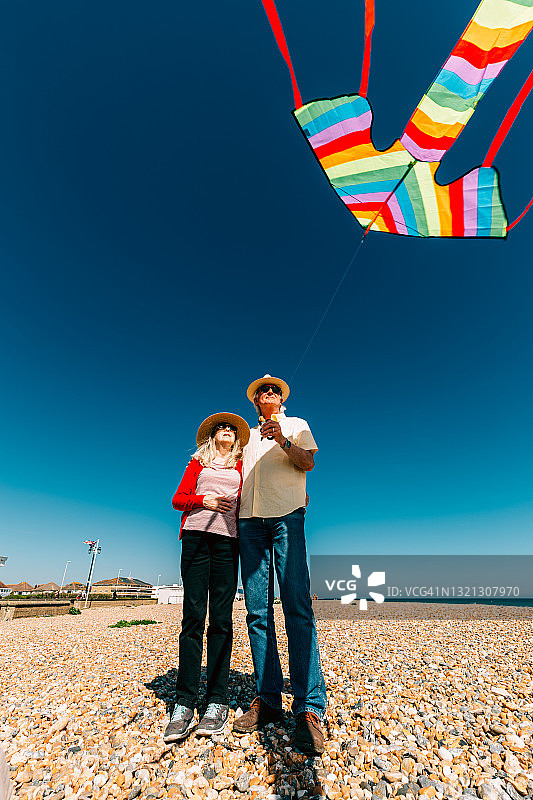 老年夫妇在海滩放飞彩色彩虹风筝图片素材