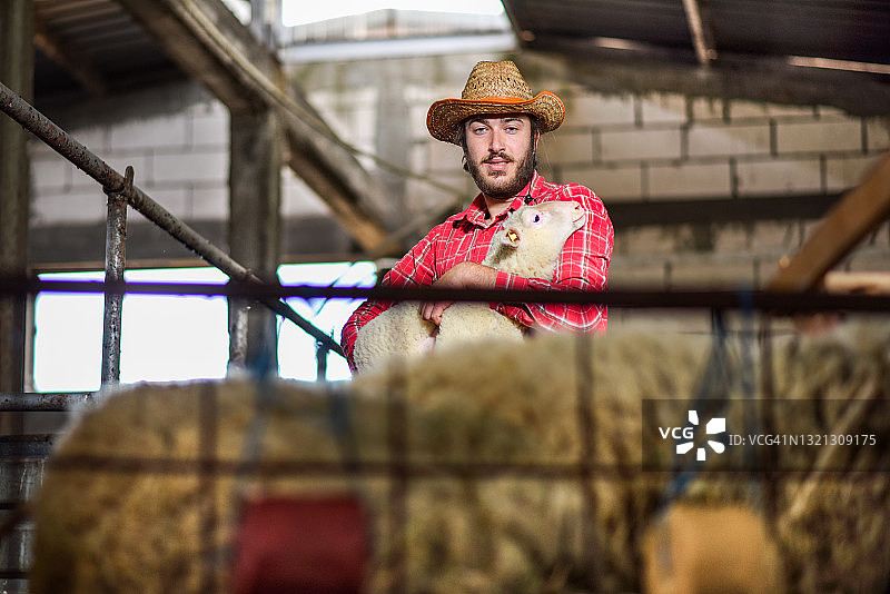 年轻的现代农民抱着小羊羔图片素材