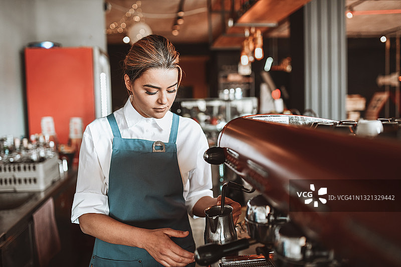 专注的女咖啡师在咖啡馆制作浓缩咖啡图片素材