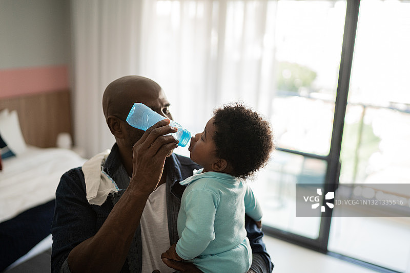 父亲在家给小儿子喂水图片素材