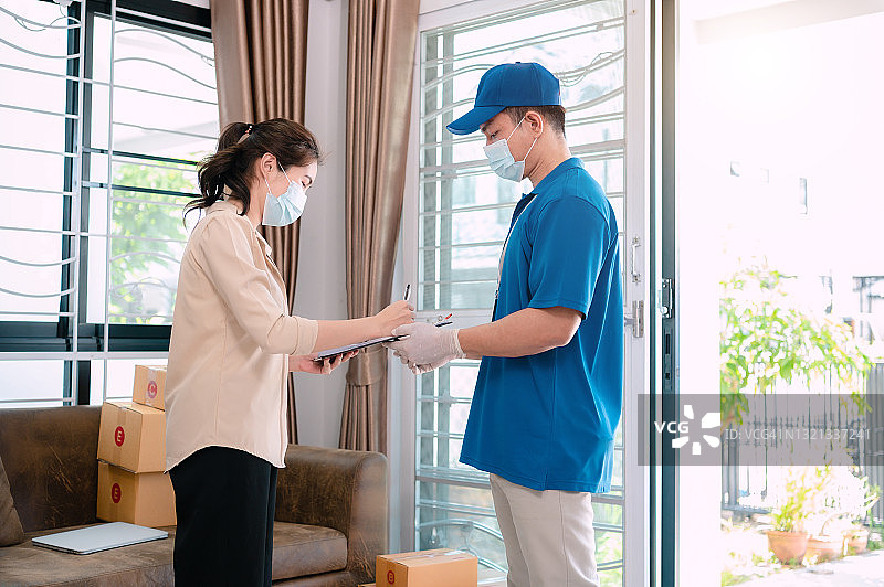 疫情期间年轻女人从送货员处收到包裹图片素材
