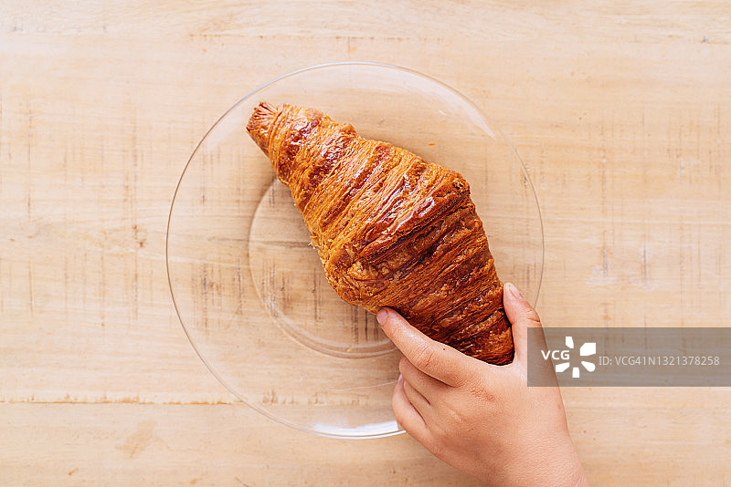 芒果木桌上玻璃盘中的新鲜黄油羊角面包图片素材