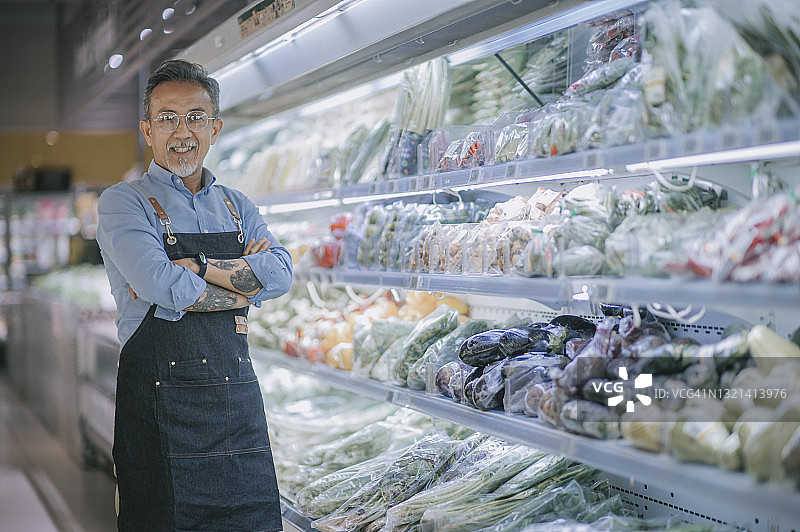 亚洲华人超市小企业主老年男人交叉双臂对着镜头微笑图片素材