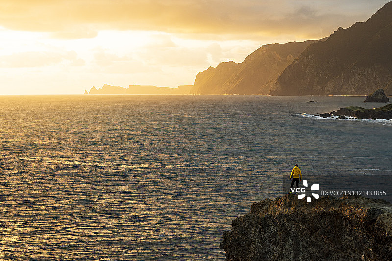马德拉群岛，在悬崖上欣赏黎明时分大海的男子图片素材