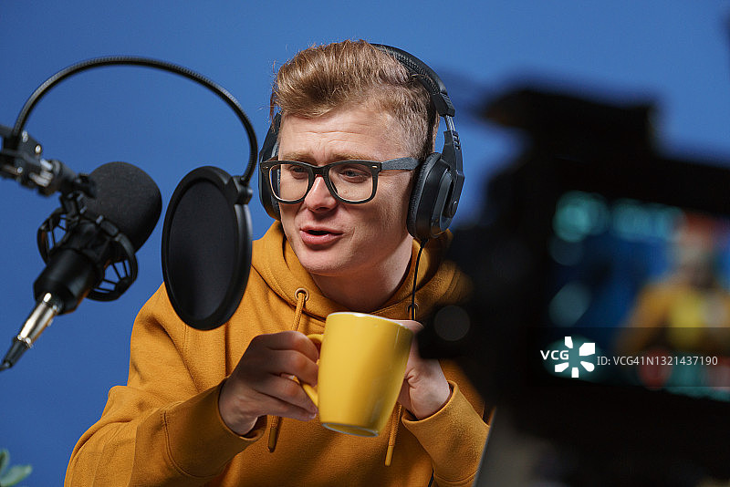 视频博主在直播时用黄色杯子喝咖啡图片素材