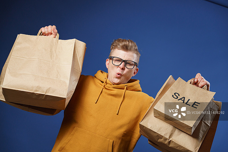 惊讶的年轻人展示着手中的许多购物纸袋图片素材