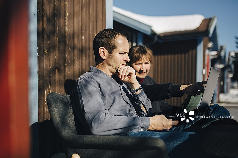 女企业家与商人坐在度假屋里，对着笔记本电脑进行讨论图片素材