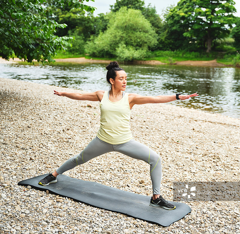年轻女子在户外练习瑜伽，做战士式图片素材