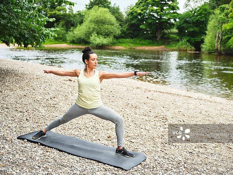 年轻女子在户外练习瑜伽，做战士式图片素材