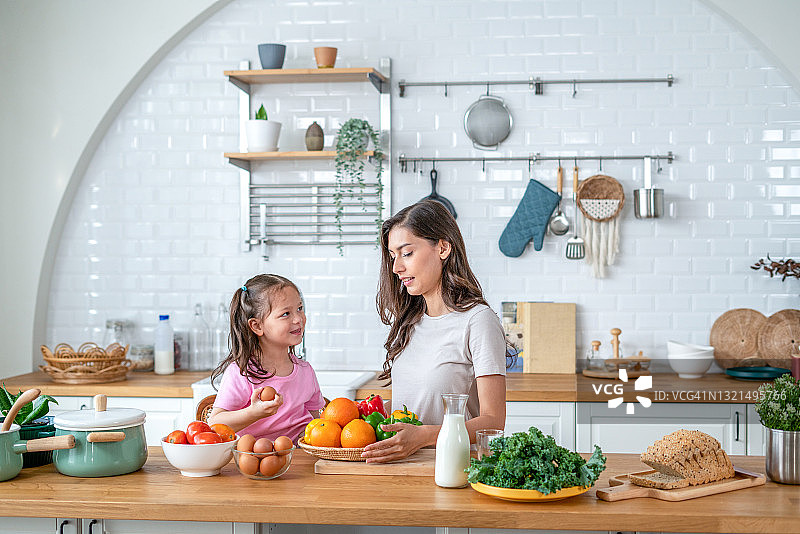 母亲在厨房和女儿一起准备食物。图片素材