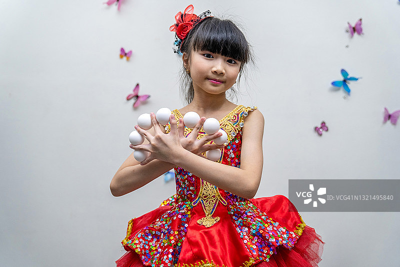 戴着高顶帽子和魔术棒在白色背景下变魔术的漂亮小女孩图片素材