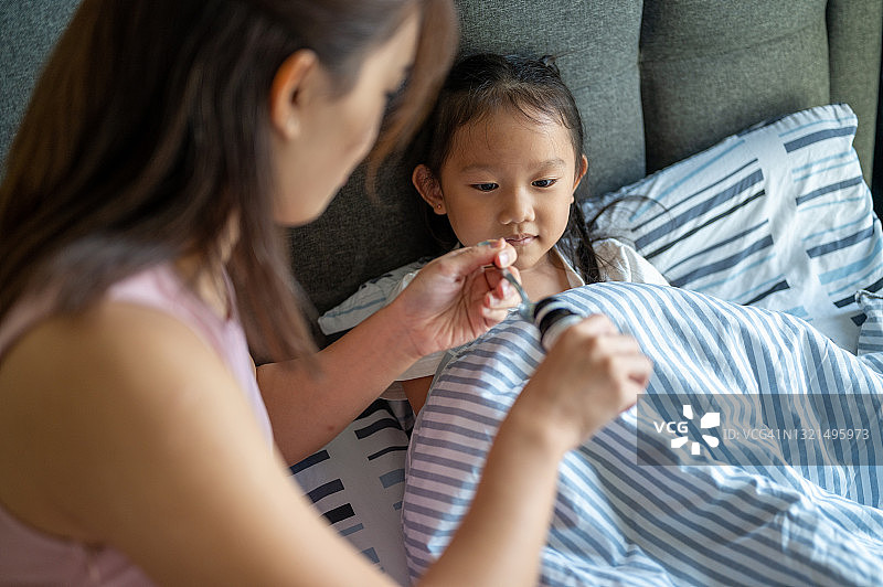 亚洲妈妈给女儿喂止咳糖浆图片素材