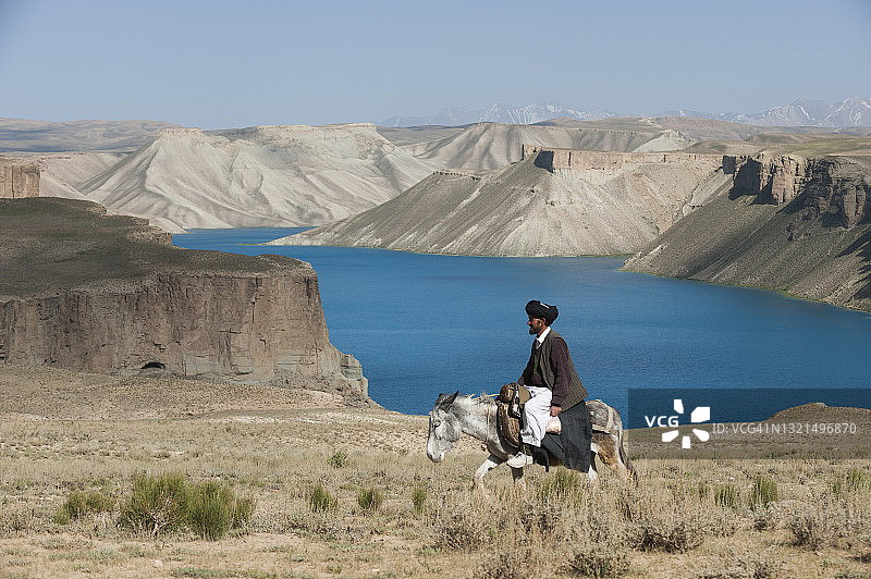 男子骑驴经过班达米尔的蓝色湖泊图片素材