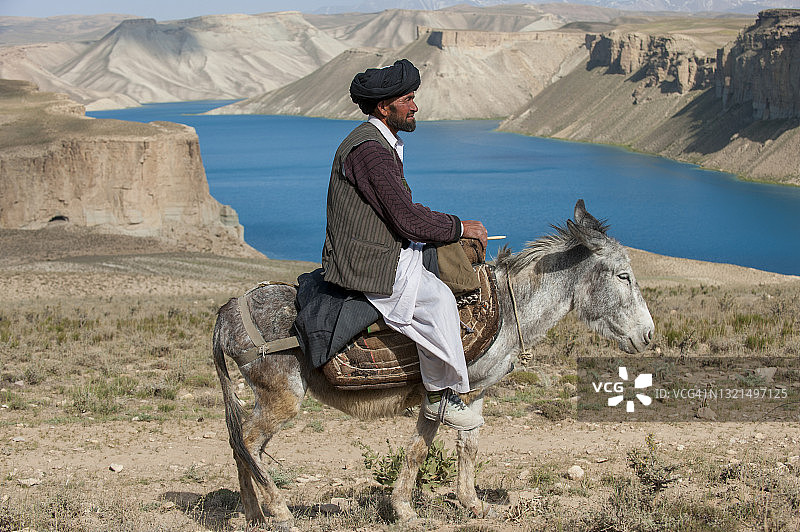 男子骑驴经过班达米尔的蓝色湖泊图片素材