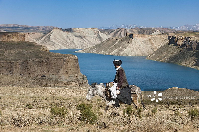 男子骑驴经过班达米尔的蓝色湖泊图片素材
