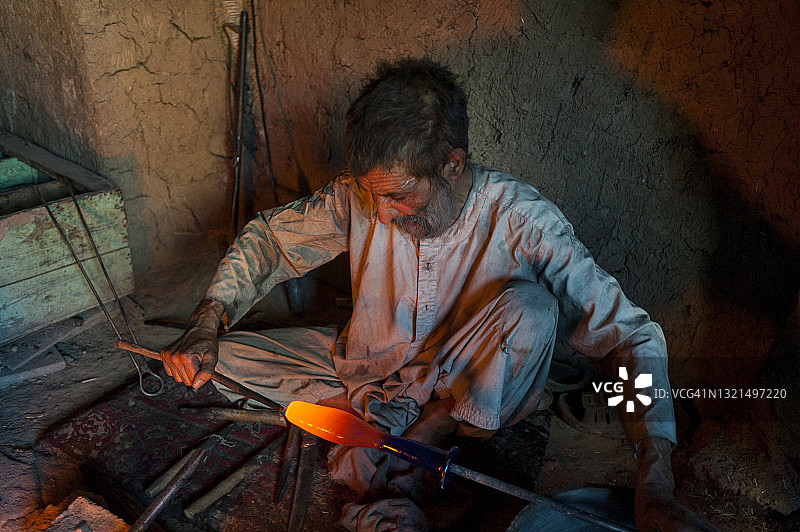 在阿富汗赫拉特的一个车间里，玻璃吹制工人正在制作一块青金石蓝色的赫拉特玻璃图片素材