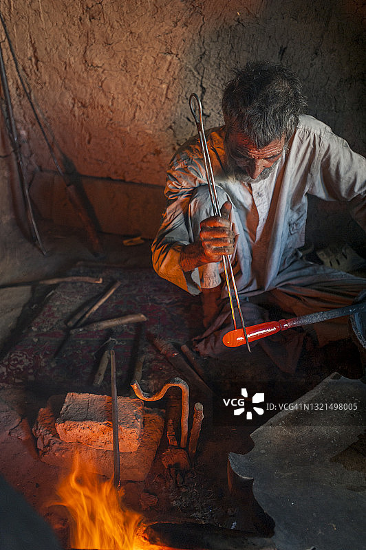 在阿富汗赫拉特的一个车间里，玻璃吹制工人正在制作一块青金石蓝色的赫拉特玻璃图片素材