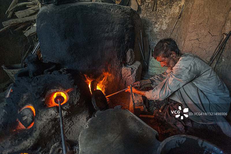 在阿富汗赫拉特的一个车间里，玻璃吹制工人正在制作一块青金石蓝色的赫拉特玻璃图片素材