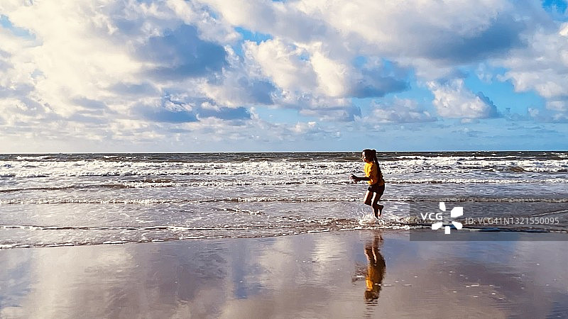女孩在北威尔士巴茅斯海滩上奔跑图片素材
